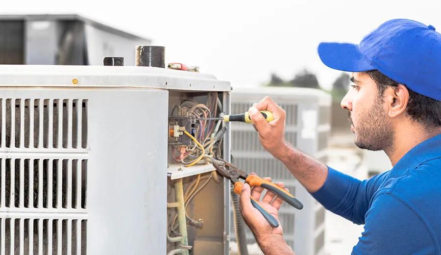 Technician installing new air conditioning thermostat for temperature control